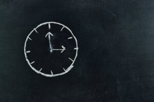 Chalk-drawn clock on a blackboard, symbolizing time and education concepts.